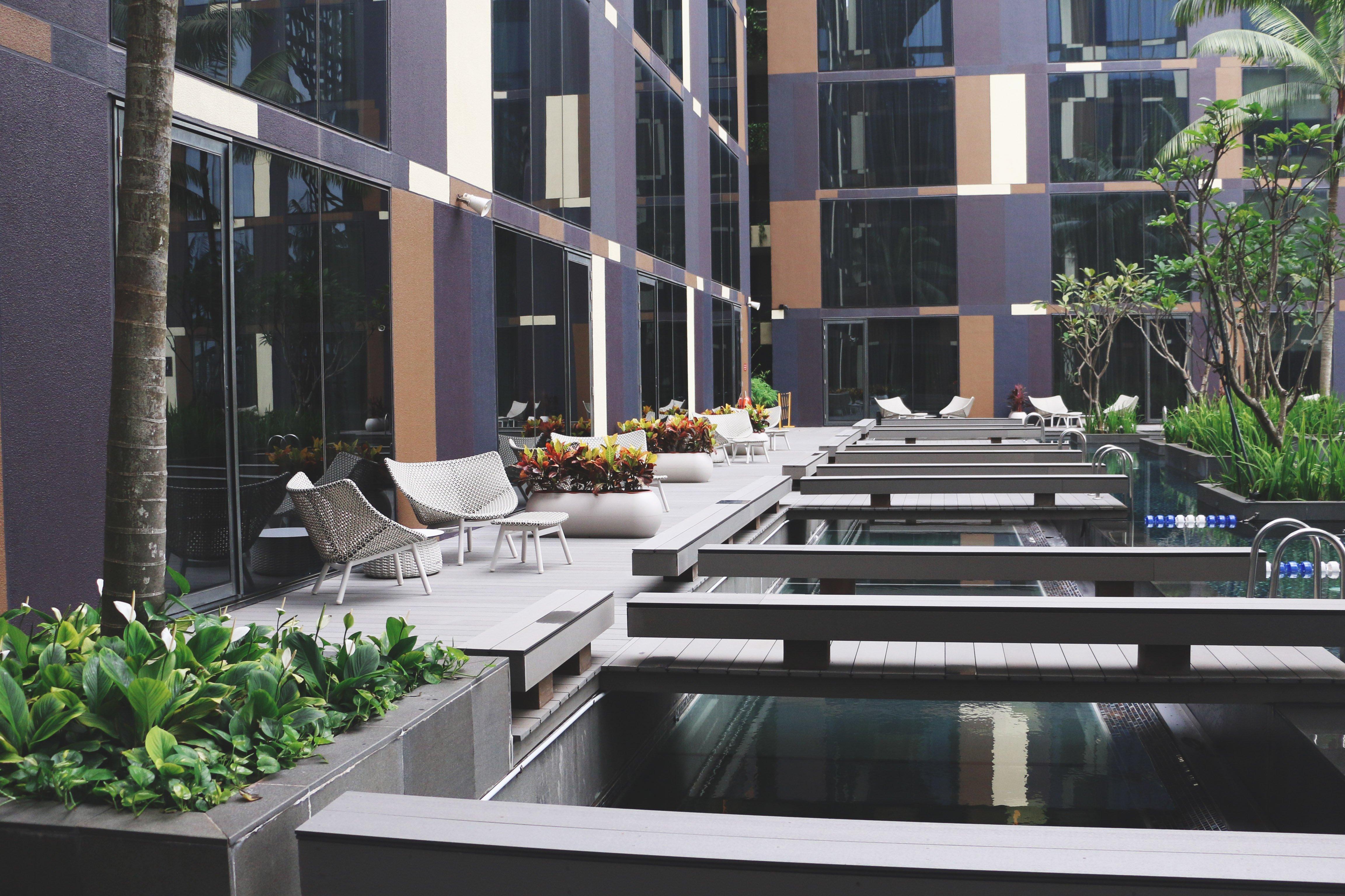 Crowne Plaza Changi Airport By Ihg Сингапур Экстерьер фото The photo shows a modern outdoor area featuring a sleek, contemporary design. There are large glass windows reflecting the surroundings, and the space includes wooden decks over water features. Comfortable seating areas are arranged along the decking