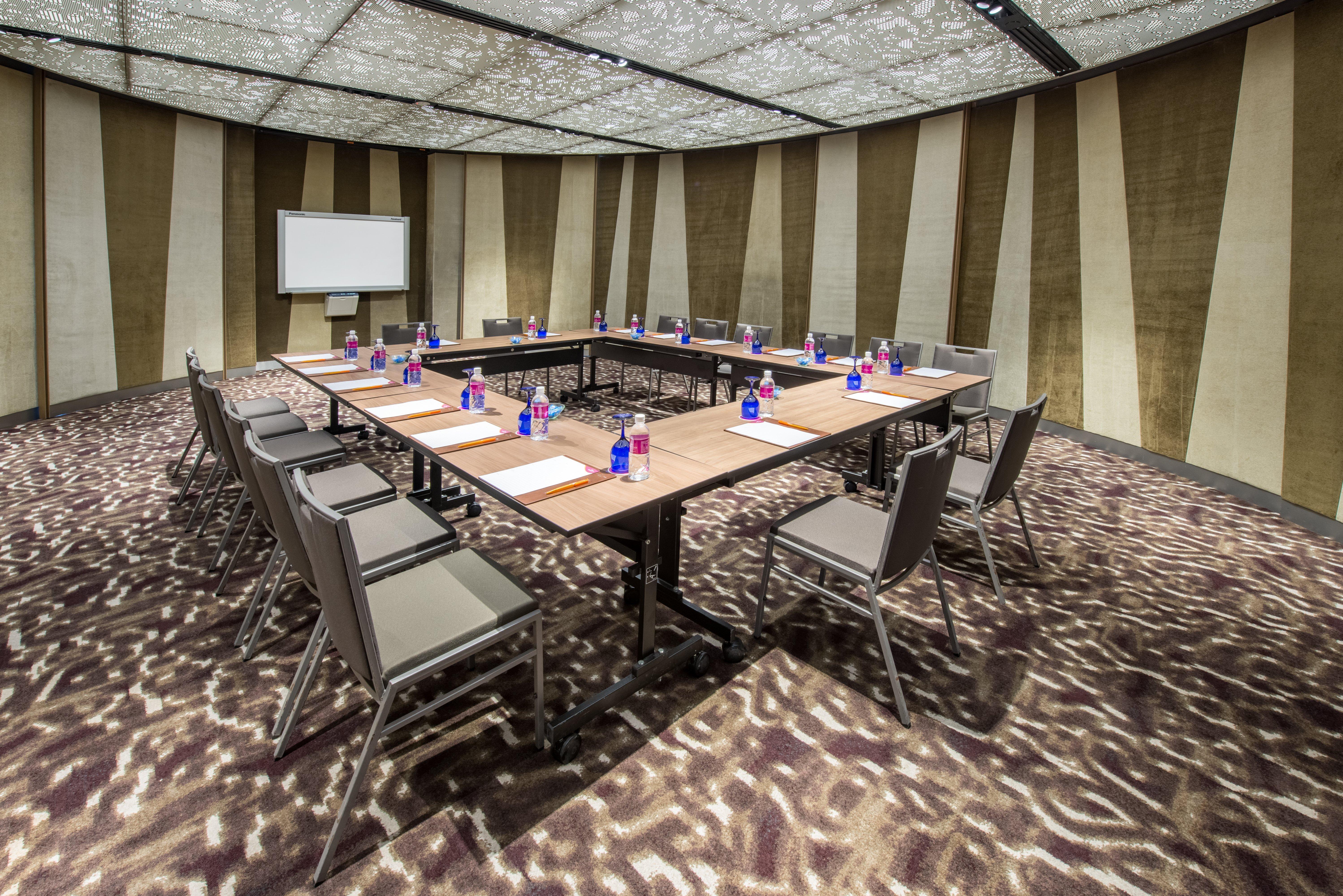 Crowne Plaza Changi Airport By Ihg Сингапур Экстерьер фото The photo depicts a conference room set up for a meeting. There is a large rectangular table in the center with chairs arranged around it. Each seating area has a small bottle of water and a notepad, suggesting it's prepared for attendees. The room f