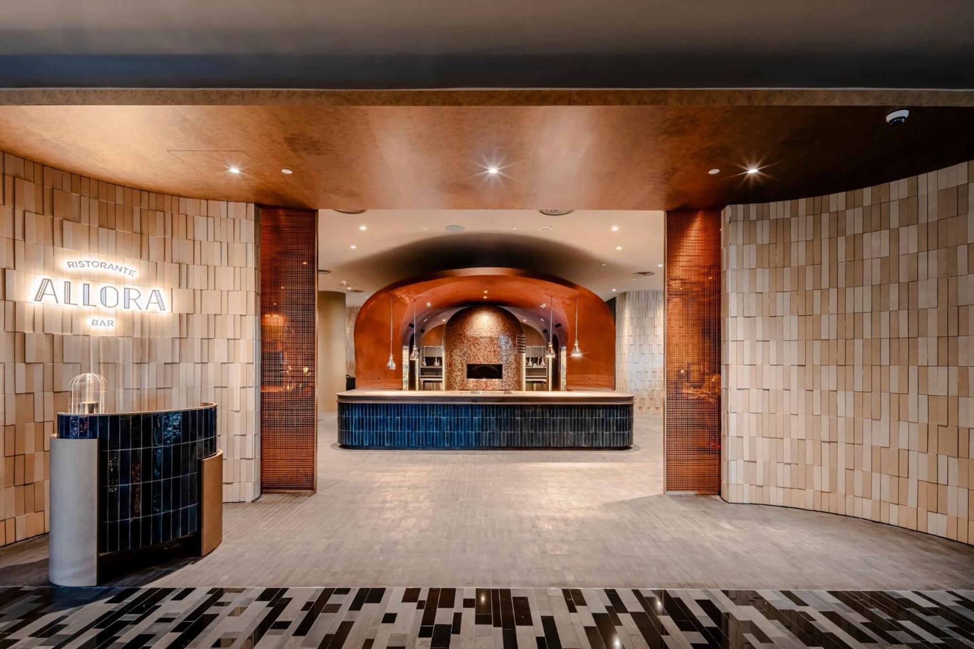 Crowne Plaza Changi Airport By Ihg Сингапур Экстерьер фото The photo shows a modern reception area, characterized by a stylish and elegant design. The space features a combination of textured wall panels, including light-colored tiles and warm-toned materials. In the center, there is a sleek reception desk a