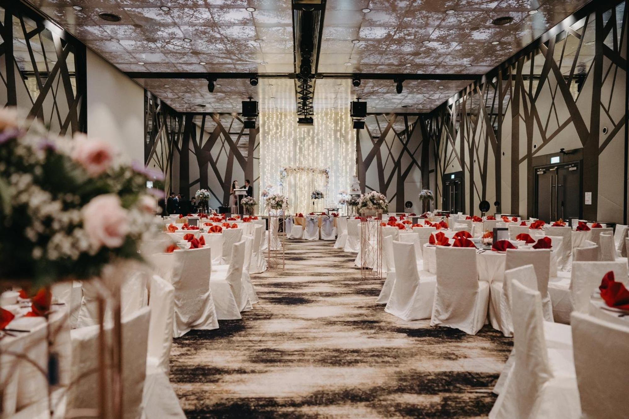 Crowne Plaza Changi Airport By Ihg Сингапур Экстерьер фото The photo shows an elegantly decorated banquet hall set up for an event, likely a wedding or formal gathering. The room features rows of tables covered in white tablecloths, each adorned with vibrant red flowers. There are also floral arrangements on