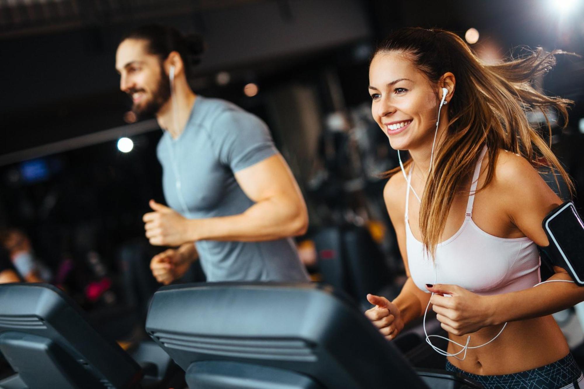 Crowne Plaza Changi Airport By Ihg Сингапур Экстерьер фото The photo shows two individuals running on treadmills in a gym. The woman, wearing a sports bra and workout leggings, has earbuds in and is smiling as she runs. The man, next to her, wears a fitted t-shirt and appears to be focused on his workout. Bo