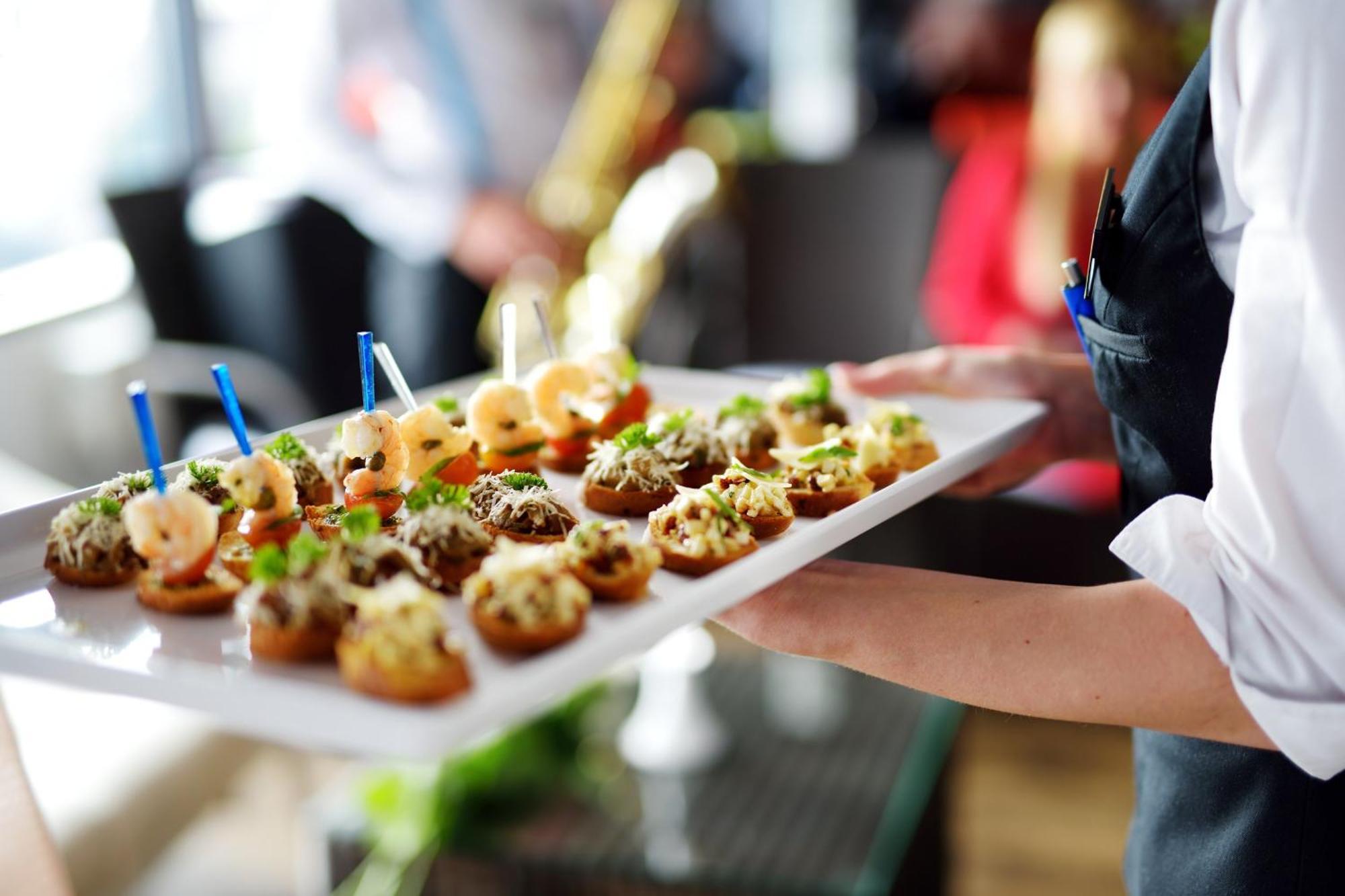 Crowne Plaza Changi Airport By Ihg Сингапур Экстерьер фото The photo shows a tray of appetizers being held by a waiter. The tray is filled with various small bites that appear to be decorative and gourmet. Some of the appetizers feature toppings such as shrimp and what looks like a mix of herbs or spreads. T