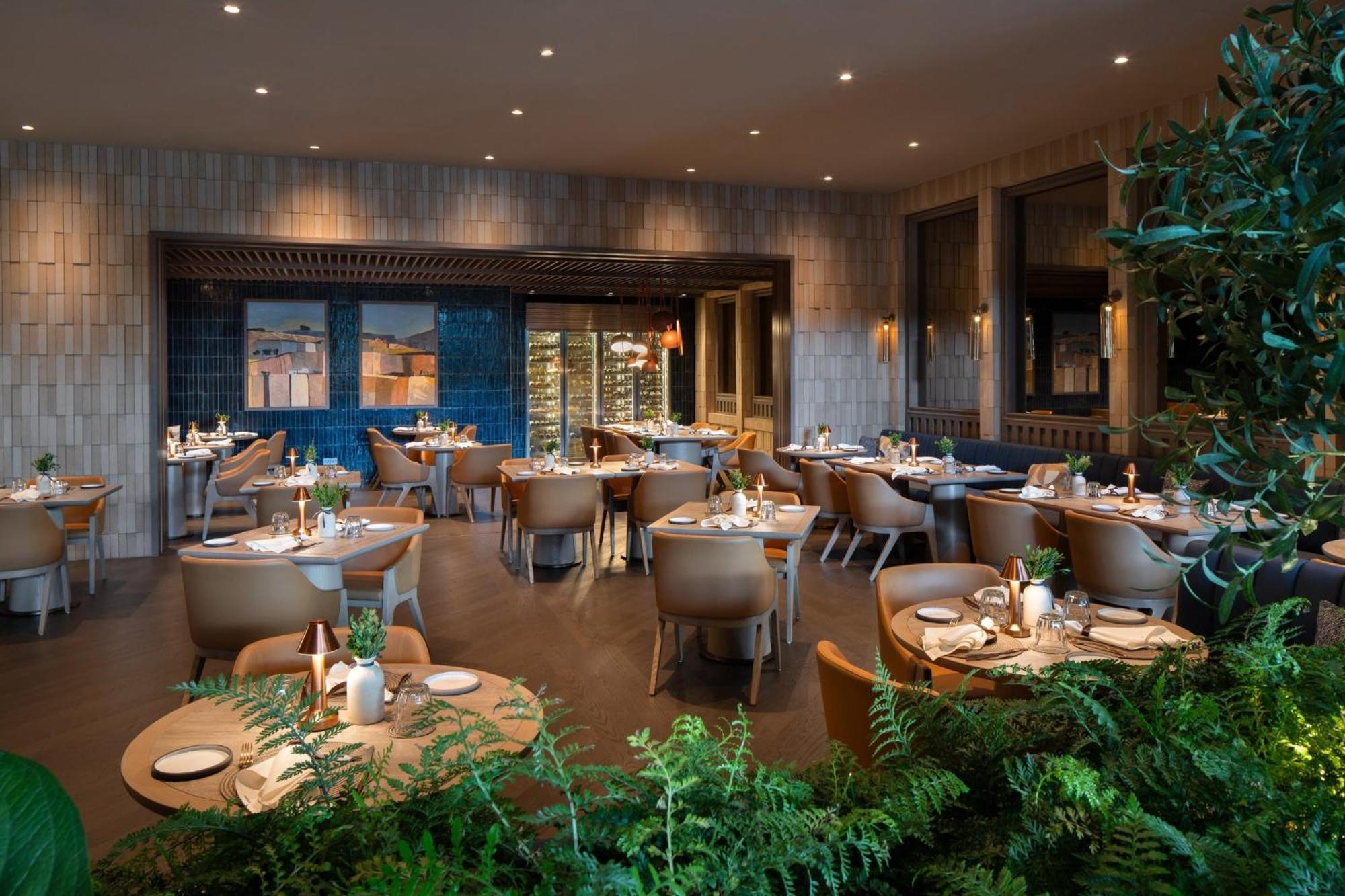 Crowne Plaza Changi Airport By Ihg Сингапур Экстерьер фото The photo shows an upscale restaurant interior. It features multiple tables set with plates and decorative items, arranged in a spacious area. The design includes modern furnishings, with light wood and neutral tones dominating the decor. There are l